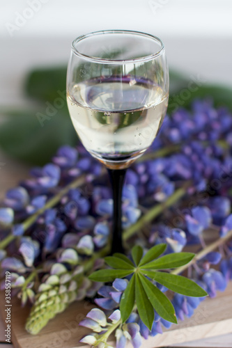 a bottle of champagne with a glass. Flowers on the background of a wooden Board with an alcoholic drink.