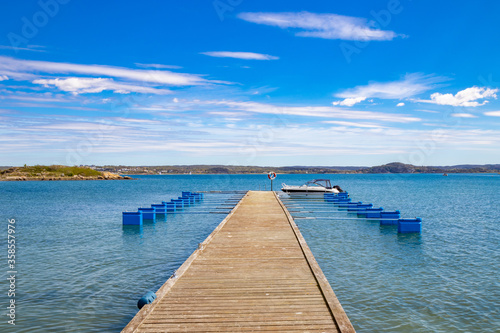 Jetty with boat against blue sky and distant coastline © Andreas Bergerstedt