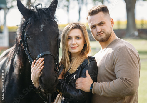 Young beautiful couple with a horse at sunset.