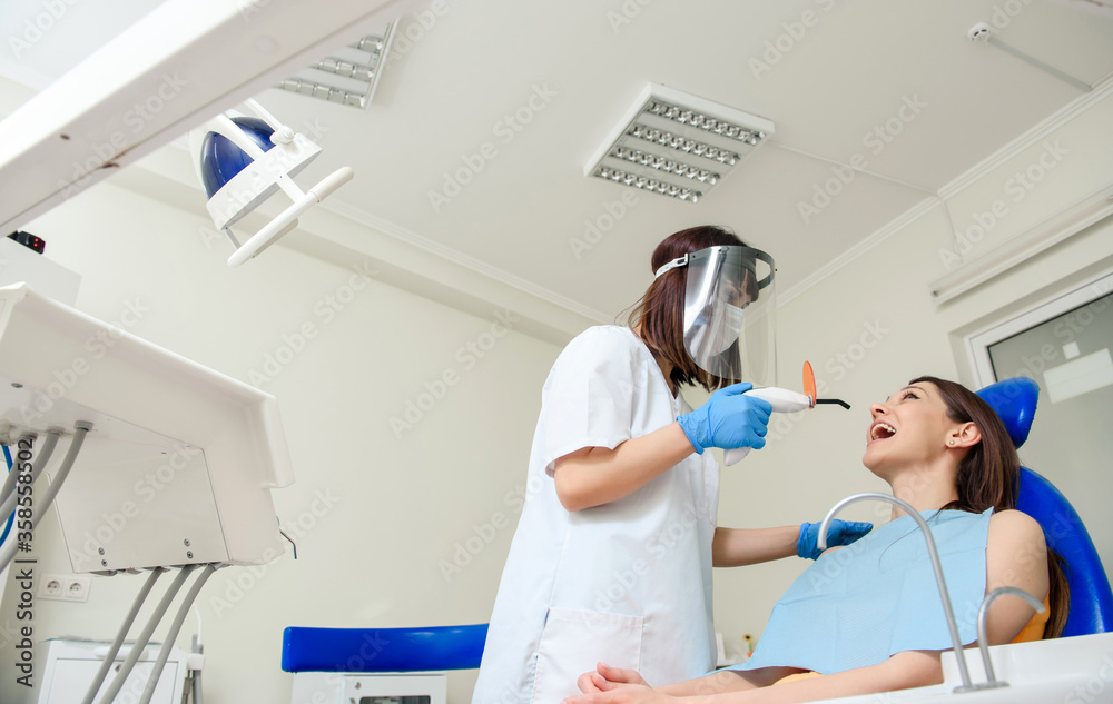 Obraz premium The dentist is using the photopolymer light for finishing the dental filling treatment in dentistry.