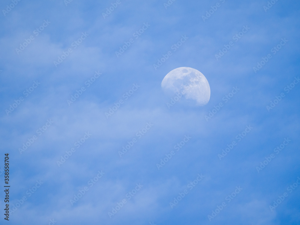 Looking up into a blue sky with an illuminated moon during the daylight hours