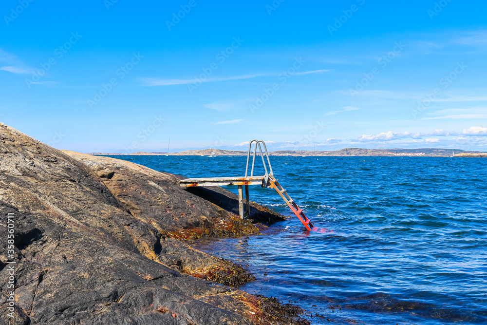 Swimming ladder from cliff down into the ocean on a bright and sunny day
