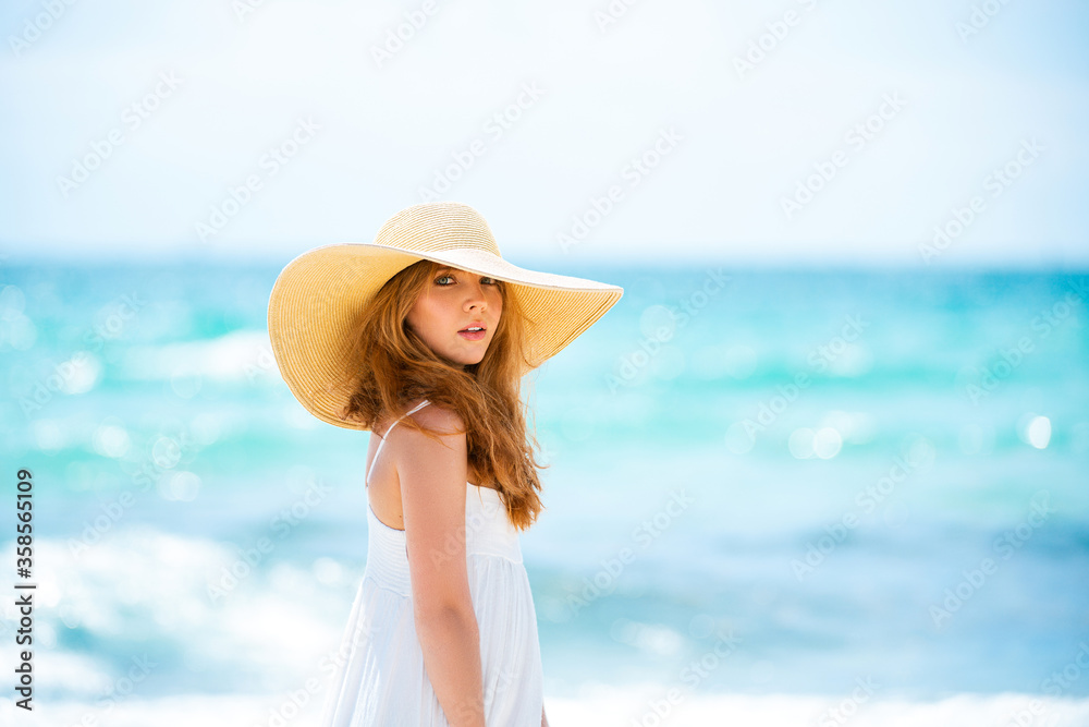 Portrait of a beautiful woman in a straw hat. Beautiful redhead woman in hat at the sea. Woman sensual. Beautiful young woman relaxing on beach.