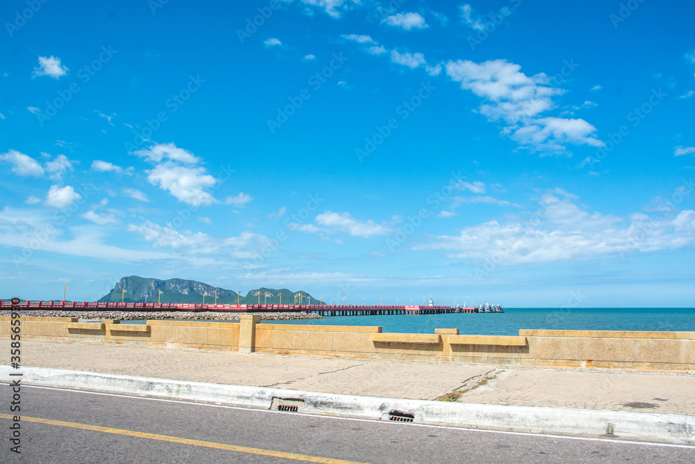 Long red pier or a bridge to the sea with blue sky at Hua-Hin District, Thailand