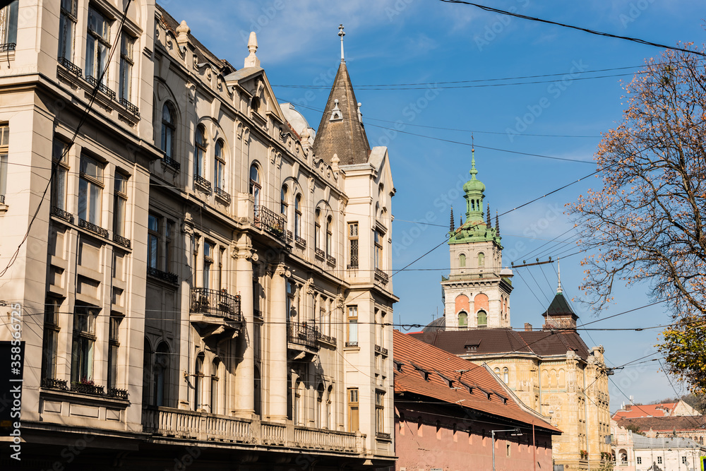 neoclassical buildings and korniakt tower against blue sky in lviv, ukraine