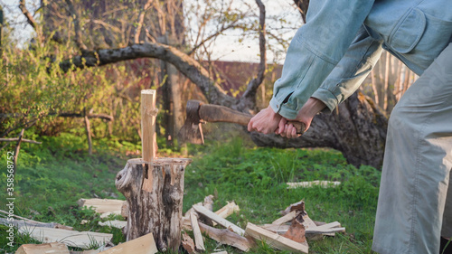 Man chops wood on a wooden pad. Rusty axe cuts log
