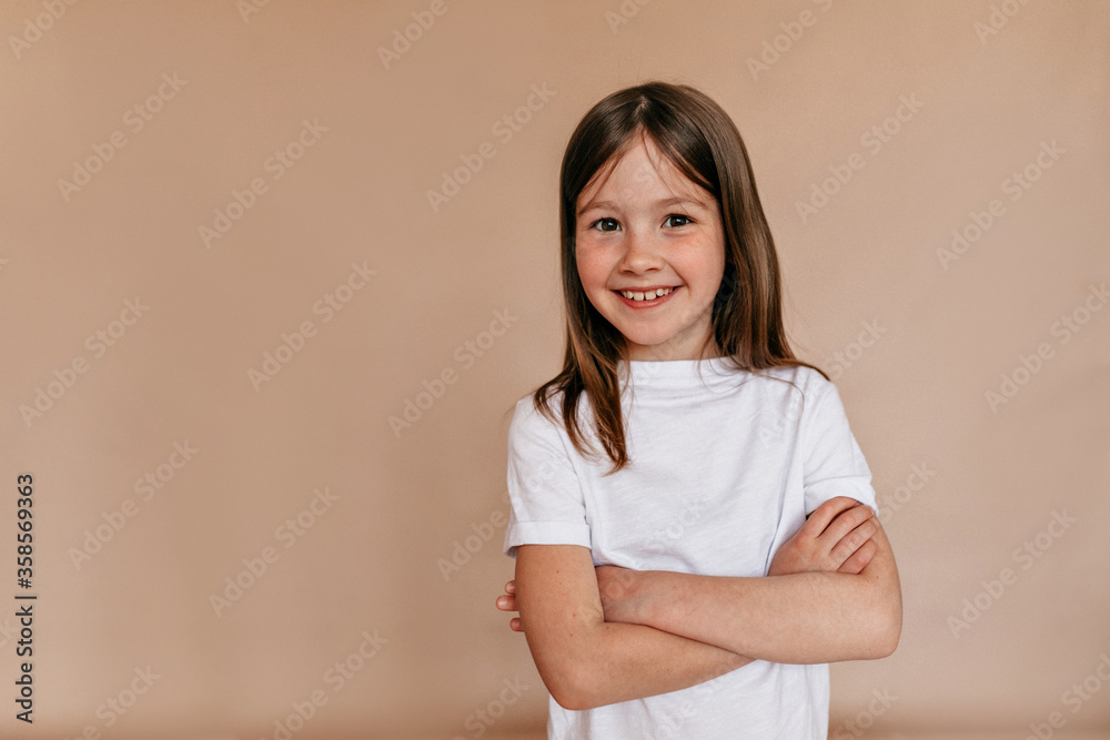 Studio shot of little charming lady wearing white t-shirt posing at camera over isolated background with great smile. Studio shot of little charming lady wearing white t-shirt posing at camera over isolated background with great smile.