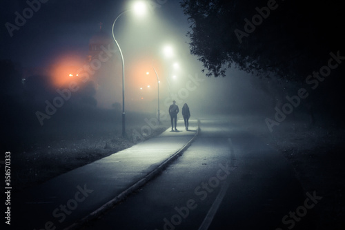a couple walks through a misty Park