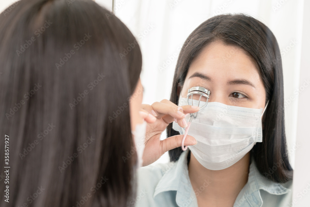 Mirror reflection asian woman wear surgical face mask make eyelash curler for go out to work after unlock Coronavirus lockdown. Reopenning , restart, Self-quarantine and social distancing concept.