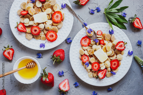 Pancake cereal, trendy food. Mini cereal pancakes with butter, honey, and strawberries.