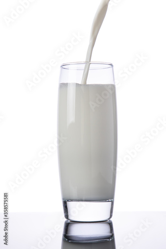 Pouring milk into a glass, isolated on white background