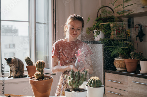 Konstfotografi A young woman replants and water cacti at home