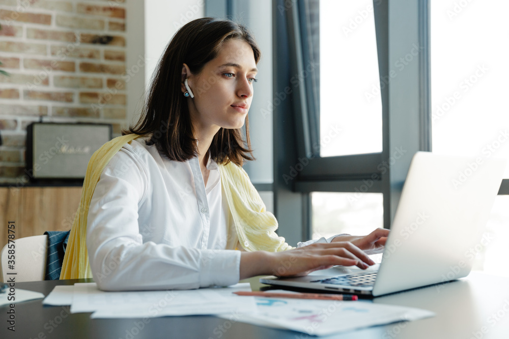 Attractive young brunette woman working on laptop computer Attractive young brunette woman working on laptop computer