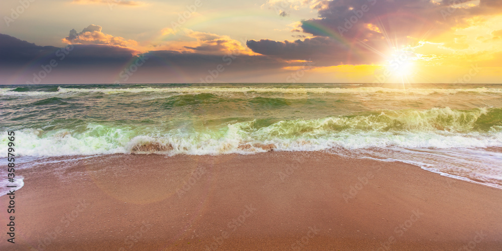 sandy beach and turquoise sea at sunset. great view of waves rolling to the coastline. wonderful weather with glowing sky and rainbow in evening light