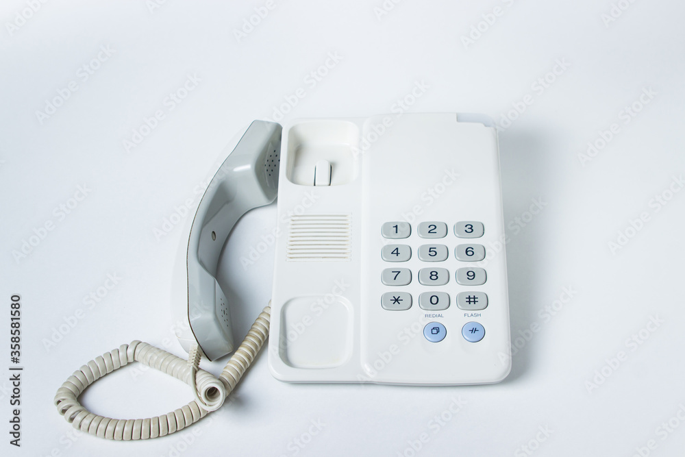 Landline phone on a white background. The handset lies next to the telephone. White landline phone with buttons Landline phone on a white background. The handset lies next to the telephone. White landline phone with buttons
