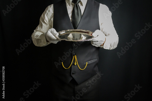 Butler in White Gloves and Waistcoat Dutifully Holding Silver Tray. Concept of Service Industry and Professional Hospitality. Dependable Servant. Copy Space for Service.