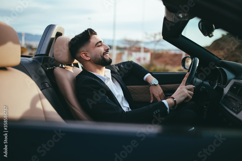 Side view of businessman driving a car at the sunset