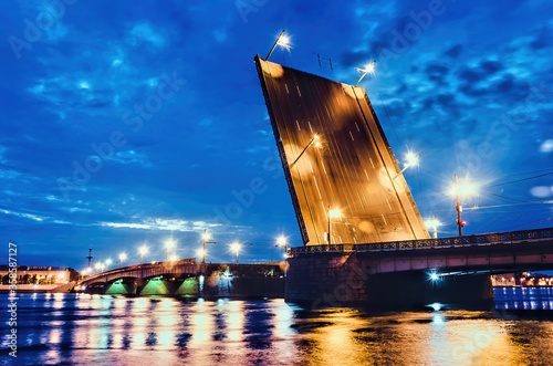 An illuminated drawbridge in Saint Petersburg at white night and reflections on water. Troitskiy Bridge. Concept of travelling to russia. Famous place.  photo