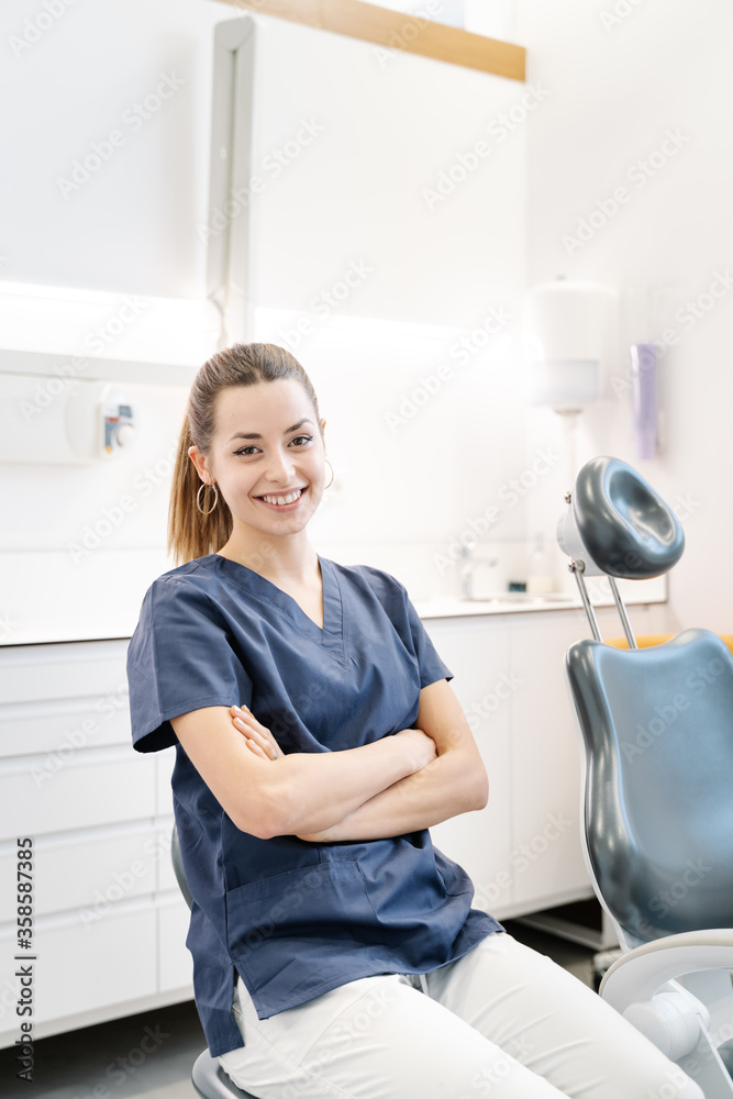 Young nurse in blue jacket smiles in the dental office before receiving the patient. Young nurse in blue jacket smiles in the dental office before receiving the patient.