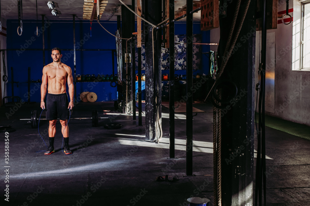 Active male athlete with naked torso using skipping rope during training while working on endurance Active male athlete with naked torso using skipping rope during training while working on endurance