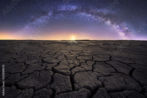 Majestic scenery of drought cracked lifeless ground under colorful Milky on background