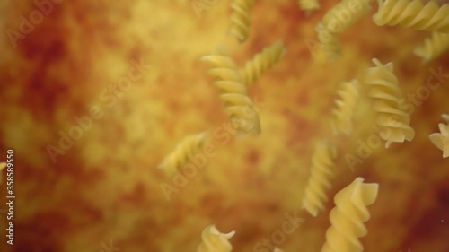 Dry pasta fusili flying diagonally on a yellow ochre background in slow motion photo