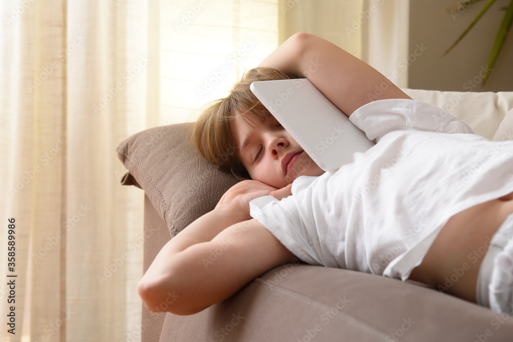 Detail of girl sleeping on sofa with tablet in arms Detail of girl sleeping on sofa with tablet in arms