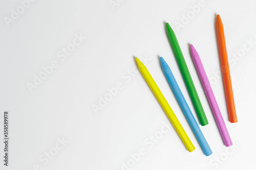 Bunch of different colorful wax crayon pencils laid oun in composition, isolated on white. Soft pastel for drawing. Close up, copy space, top view, flat lay.