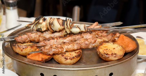 skewers on skewers with fried potatoes, sweet potatoes and onions