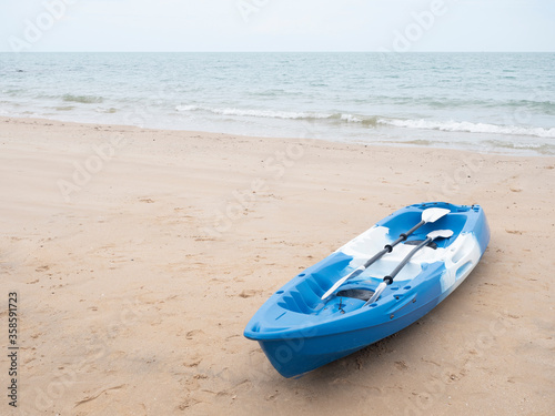 A blue kayak on the beach with copy space provided.