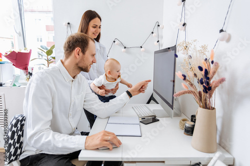 Young family working with documents and computer at home with his little son