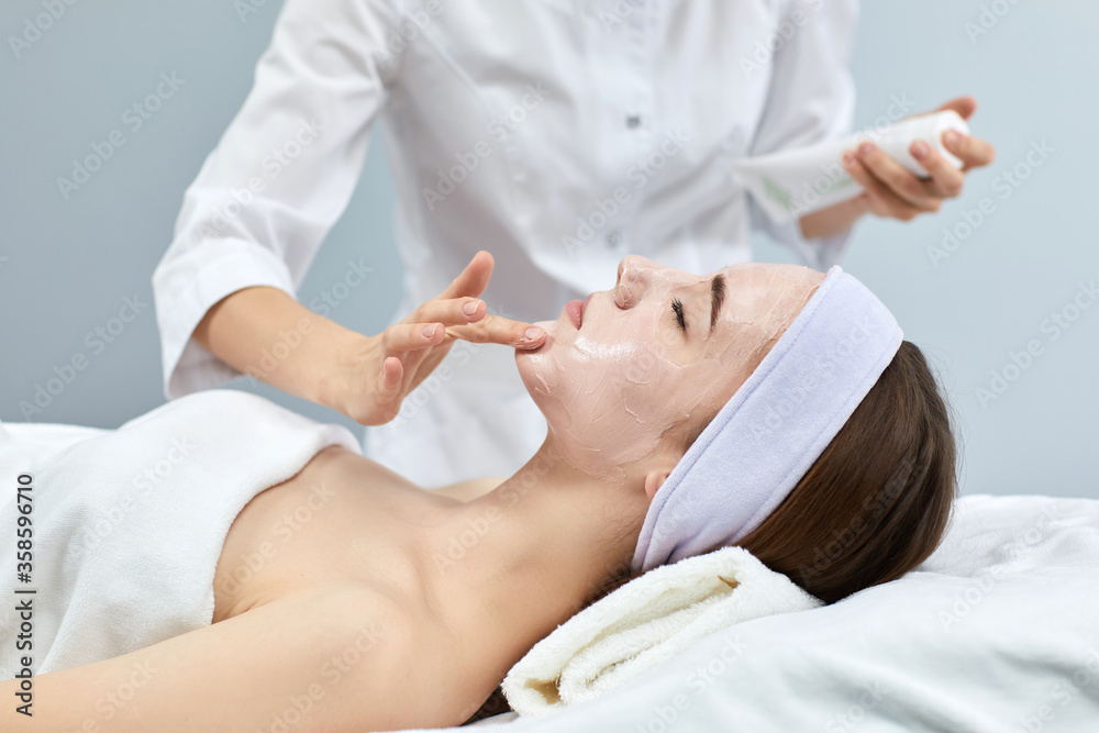 beautician applies the mask to the face of beautiful woman in the spa salon. spa treatments