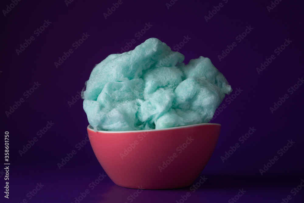 Blue cotton candy in bowl on purple background Blue cotton candy in bowl on purple background