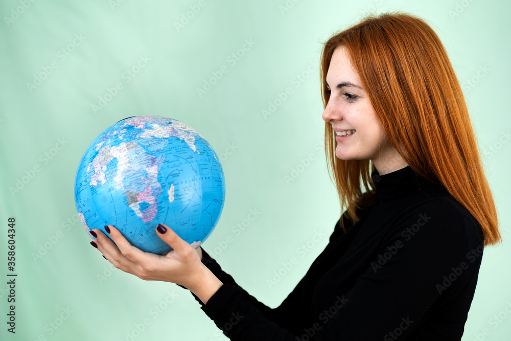 Portrait of a happy young woman holding geographic globe of the world in her hands. Travel destination and planet protection concept. Portrait of a happy young woman holding geographic globe of the world in her hands. Travel destination and planet protection concept.