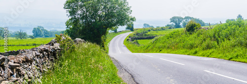 Panorama of a curved empty country road with dry stone walls