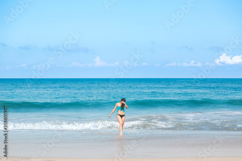 Young attractive latin surfer girl wearing a bikini walking on the beach , healthy mental and body lifestyle concept.