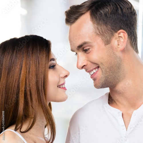 Profile side of smiling happy amazed couple at home. Face portrait image of standing close and looking at each other models in love concept. Man and woman posing together. Square composition.