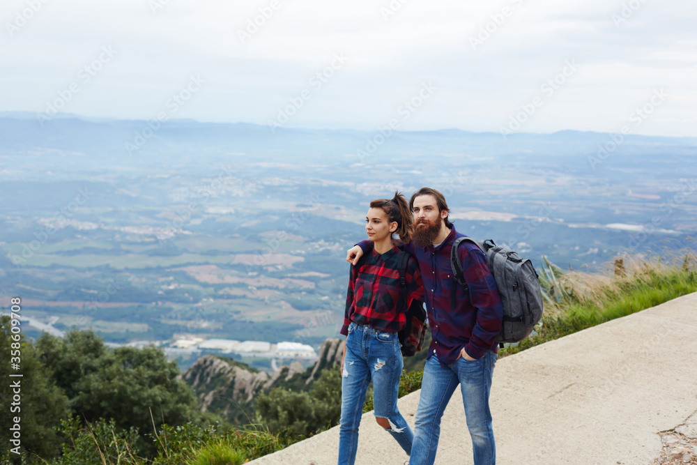 Romantic couple of hikers enjoying outdoors nature walking on the mountain trail with beautiful view on background