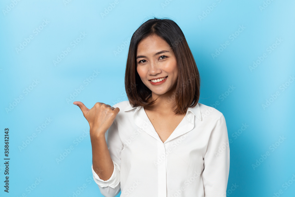Happy asian young woman smiling against made finger thumbs up OK gesture on blue background Happy asian young woman smiling against made finger thumbs up OK gesture on blue background