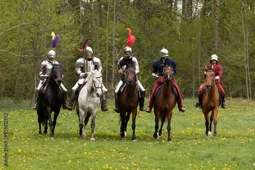 Vászonkép A knight in vintage armor of the 15th century rides a horse across a field for a