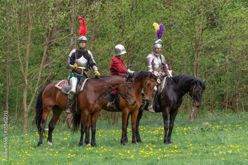 A knight in vintage armor of the 15th century rides a horse across a field for a tournament