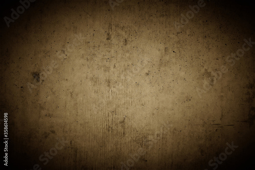 Old brown concrete wall with strong dark vignette as a highlighting background in a rustic industrial design with space for text and logos.