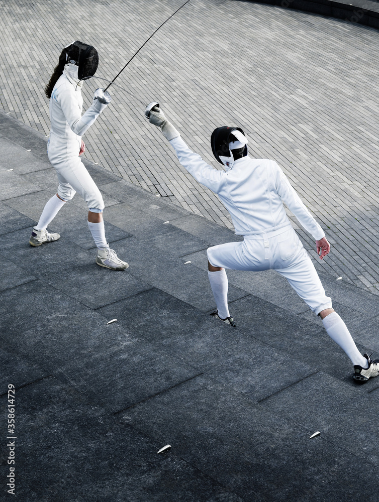 Two fencers fencing outside together Two fencers fencing outside together