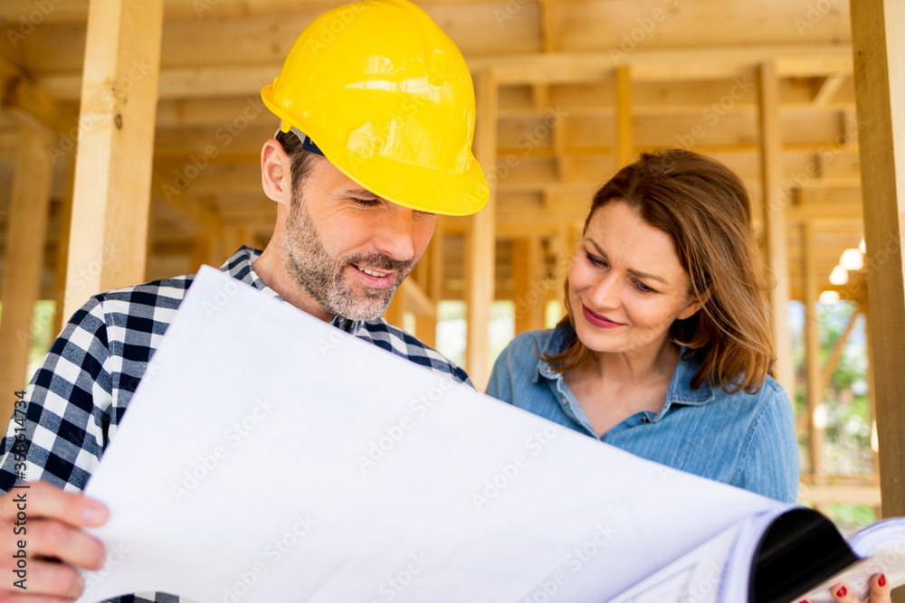 Female investor meeting with architect or engineer on construction site of her new house looking at blueprints Female investor meeting with architect or engineer on construction site of her new house looking at blueprints