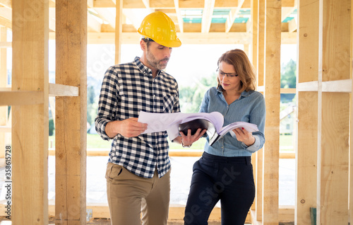 Female homeowner consults blueprints with architect or engineer on construction site of her new house