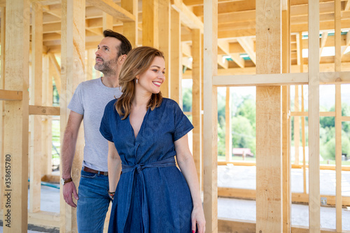 Fascinated couple walking in their new house under construction, dreams come true