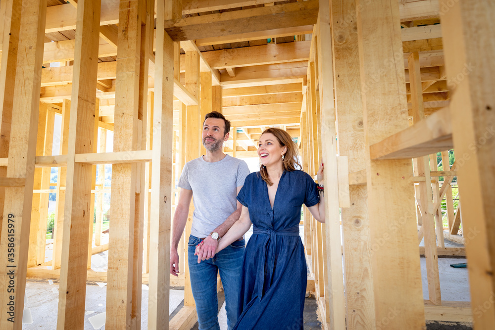 Fascinated couple walking in their new house under construction, dreams come true