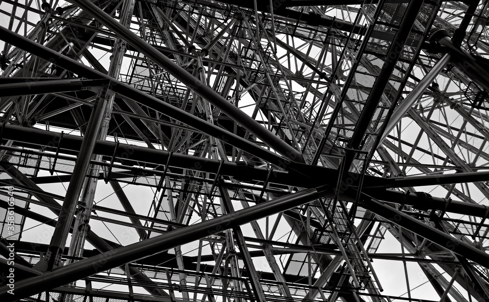 Looking up at numerous intersecting steel supports on an overcast day