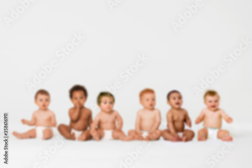 Blurred photo of Row of six multi ethnic Babies smiling in studio