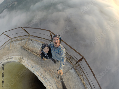 Camping on top of a smoke stack chimney, surrounded by fog and mist underneath the top of the building, sunrise